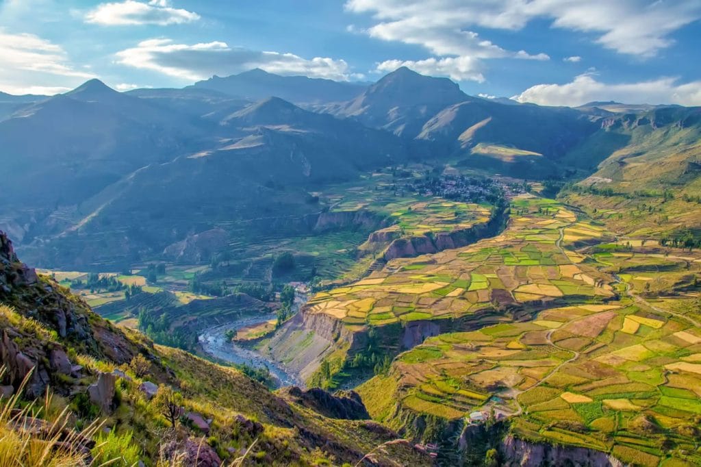 Vista aérea de las extensas terrazas y andenería preinca del Valle del Colca, con el río Colca serpenteando a través de la formación.