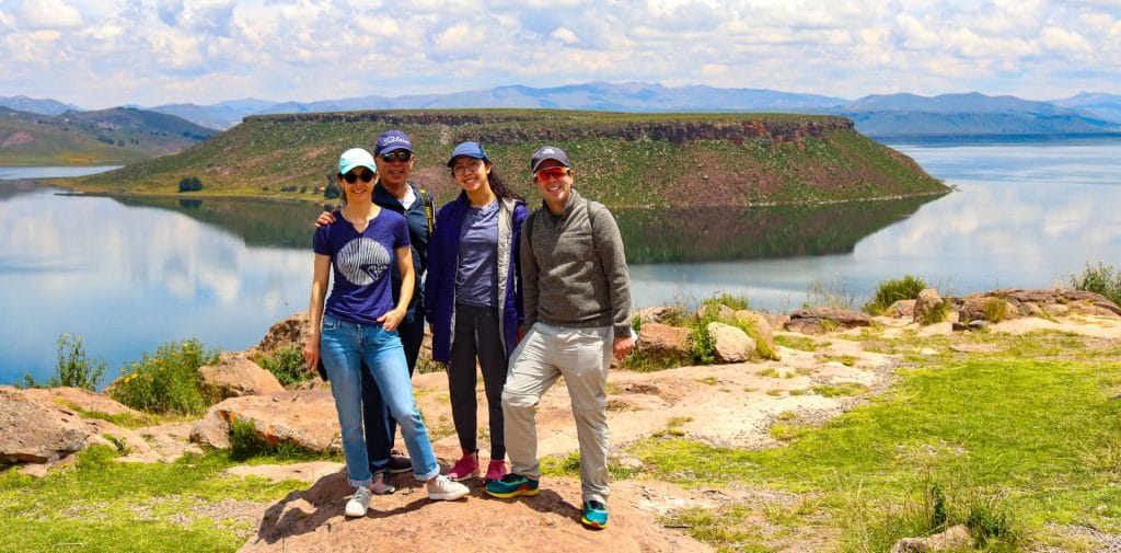 Turistas en la explanada del complejo arquelógico de Sillustani, atrás se visualiza la isla Umayo.