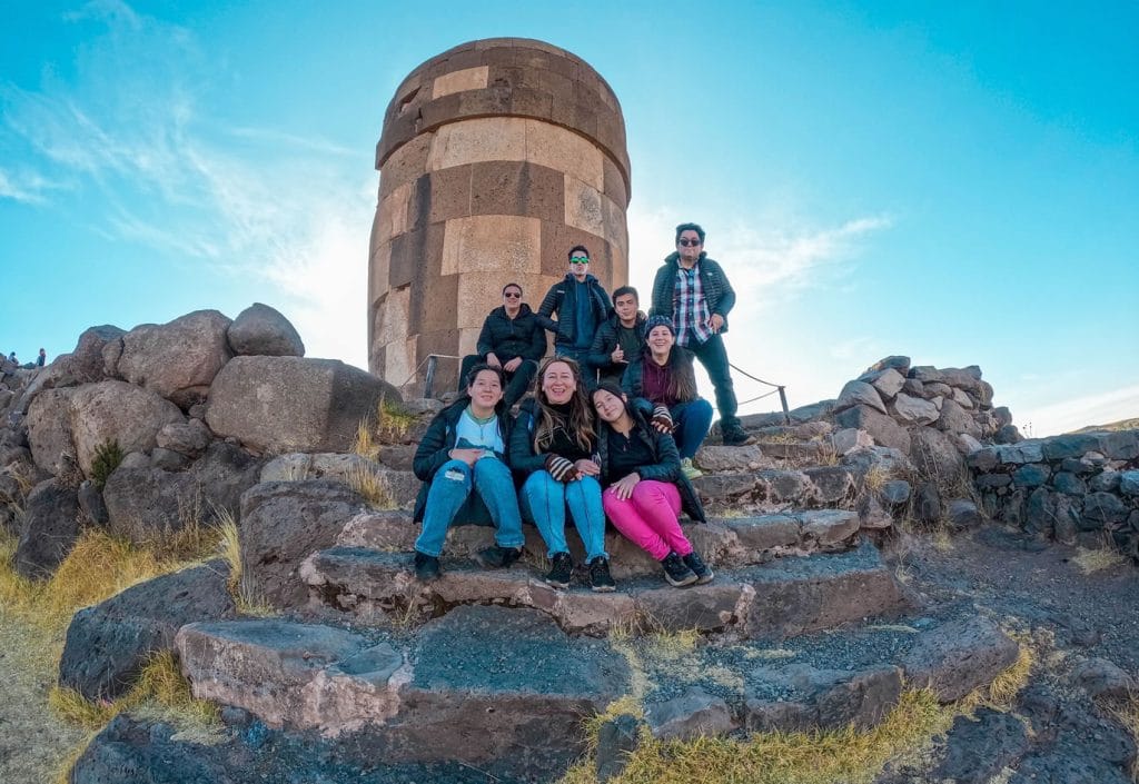 Vista desde la parte inferior de una de la Chullpas funerarias de Sillustani, grupo de turistas posando en los graderíos de ascenso y descenso de la explanada.
