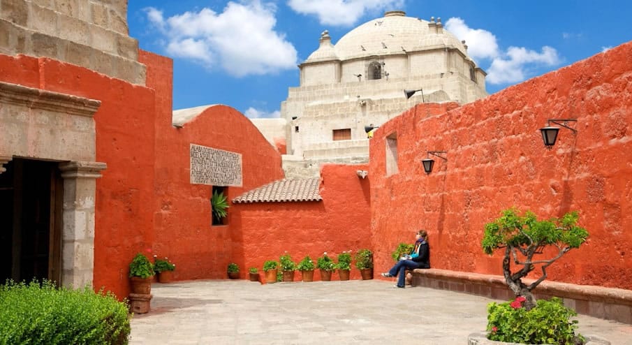 Patio interior del icónico Monasterio de Santa Catalina en Arequipa, con muros de sillar pintados en intenso color rojo intenso.