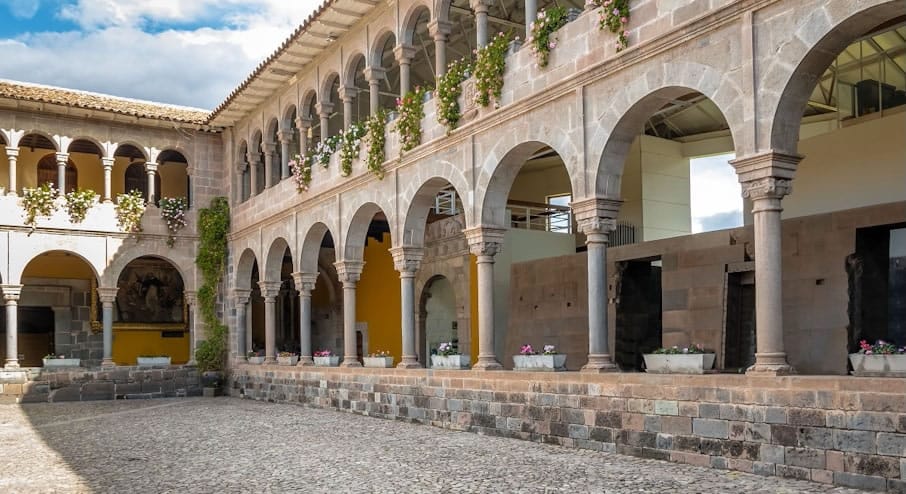 Claustro de arquitectura colonial en Cusco, destacando los sólidos muros y arcos de piedra tallada de un antiguo monasterio.