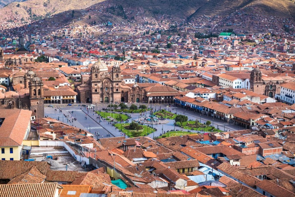 Vista panorámica de la Ciudad de Cusco desde una posición elevada, destacando la Plaza de Armas y la Catedral entre el paisaje urbano andino.