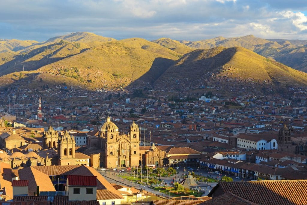 Vista panorámica de la Ciudad Imperial de Cusco al atardecer, destacando la Plaza de Armas y la Catedral bañadas por la luz dorada.