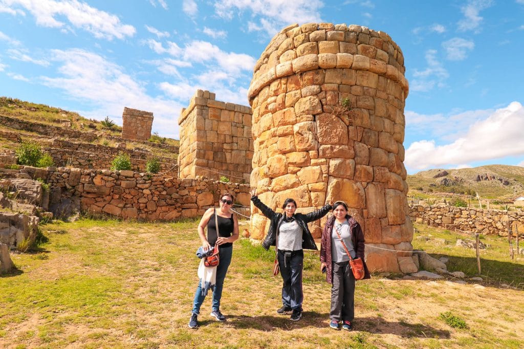 Grupo de turistas posando en el complejo arqueológico de Chullpas de Molloco, con las torres funerarias visibles en los andenes.