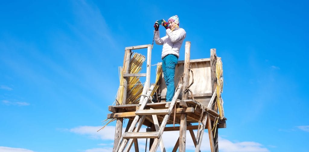 Turista tomando una fotografía panorámica con dispositivo móvil desde uno de los miradores de la isla, disfrutando la vista en los Uros.