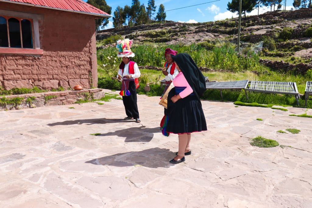 Danzantes nativos de Taquile realizando demostración cultural dentro de una casa de familia de la isla.