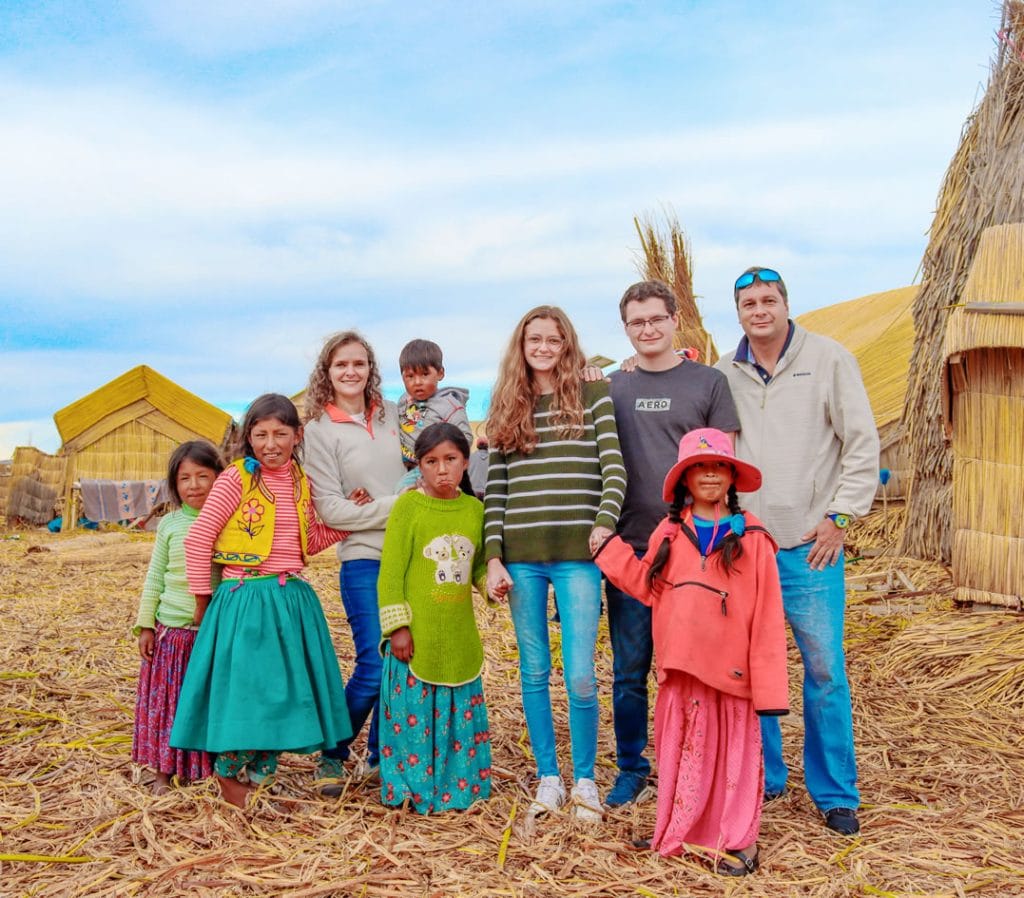 Grupo de turistas posando con niñas de la comunidad Uros en una de las islas flotantes del Lago Titicaca.