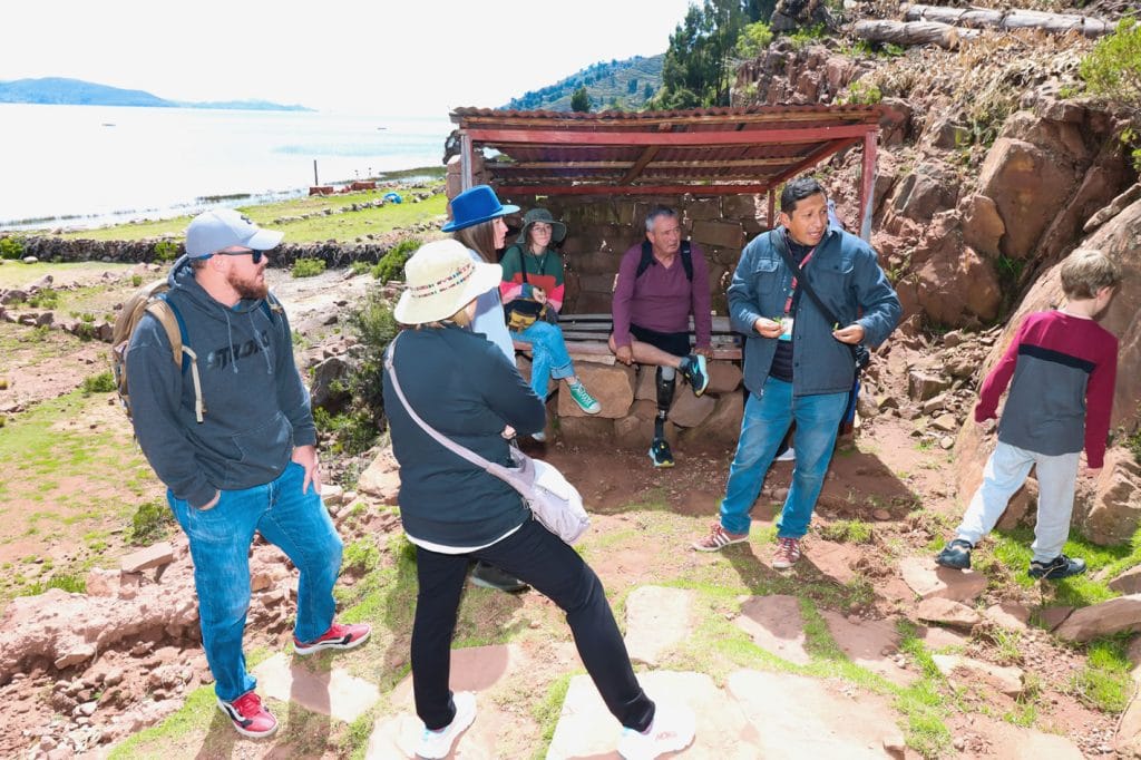 Turistas en Llachón Capachica, detrás de aprecia la isla Taquile.