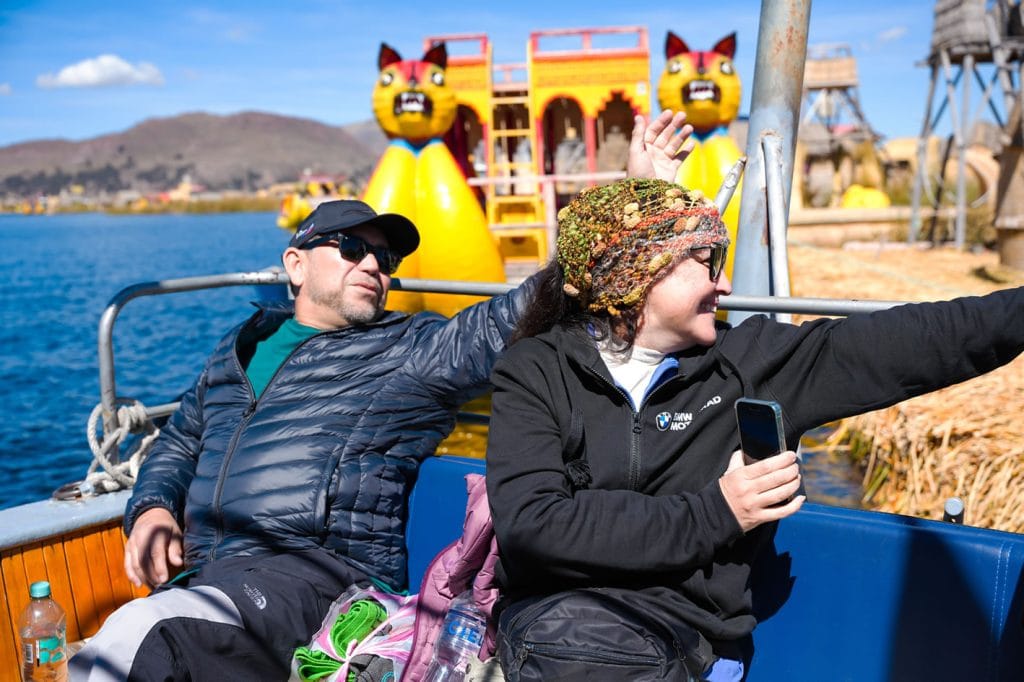 Despedida en las Islas Flotantes de los Uros: Turistas en lancha de motor se despiden de pobladores en el muelle de totora.