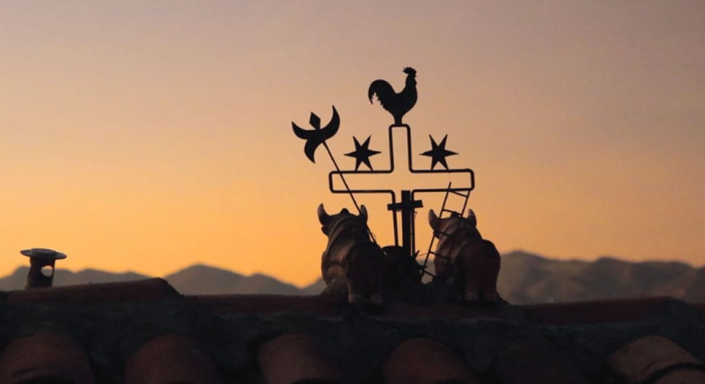 Veleta andina con gallo y Toritos de Pucará sobre el techo, al atardecer en Puno.