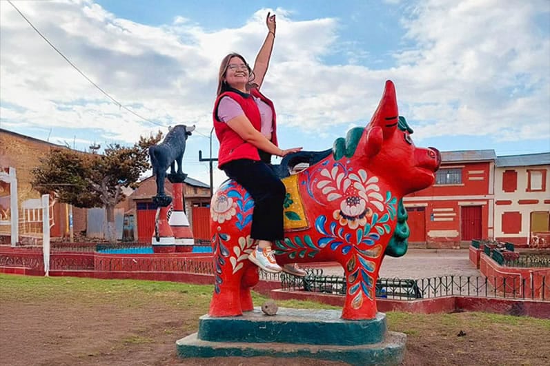Turista alegre posando sobre el icónico Monumento del Torito rojo de Pucará.