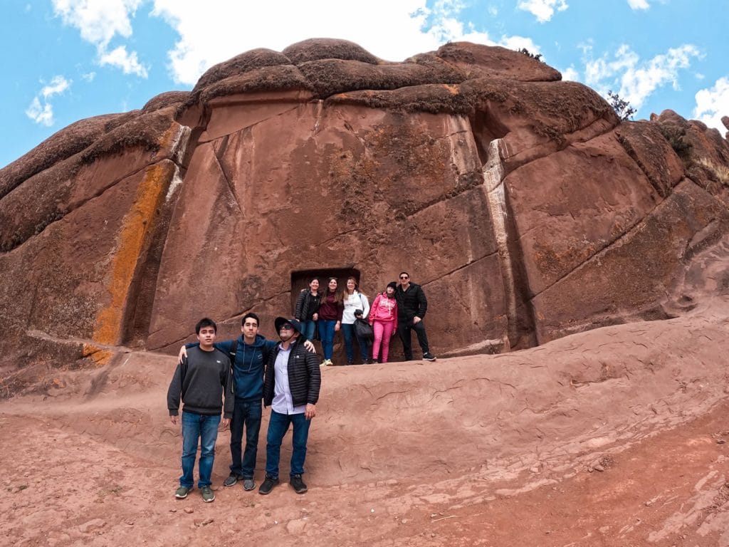 Dos grupos de viajeros posando frente a la gran Puerta de Aramu Muru (Hayu Marca), una gigantesca roca tallada en forma de portal, en el sur de Puno.