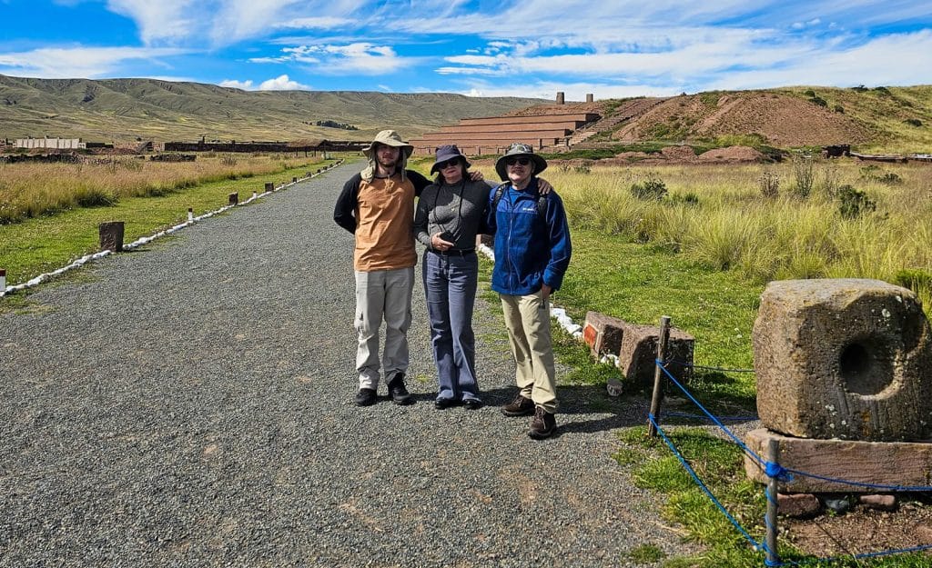 Tres turistas posan en uno de los caminos empedrados del complejo o santuario arqueológico de Tiahuanaco, explorando las ruinas preincaicas en Bolivia.