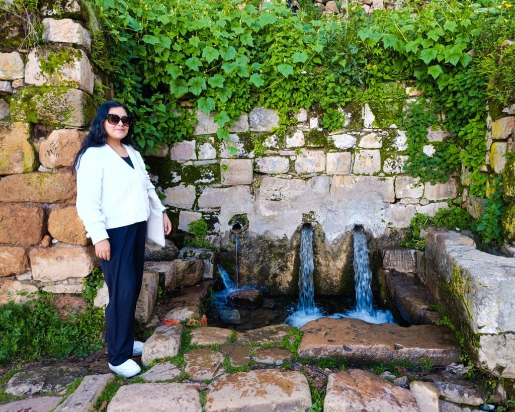 Turista posa en la Isla del Sol (Bolivia) junto a la histórica Fuente del Inca o Fuente de la Juventud, una estructura inca con piletas de agua que simbolizan el origen de la vida.