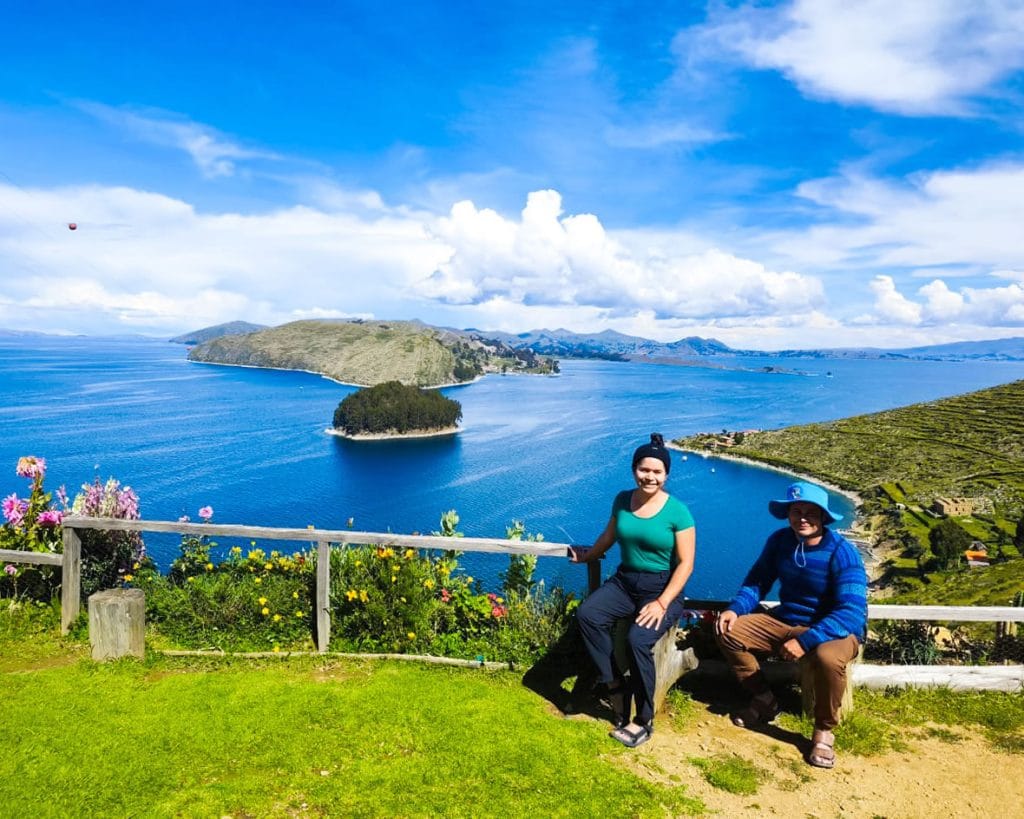 Pareja de turistas sentados y contemplando la inmensidad del Lago Titicaca y las montañas circundantes, tomada desde la Isla del Sol en Bolivia.