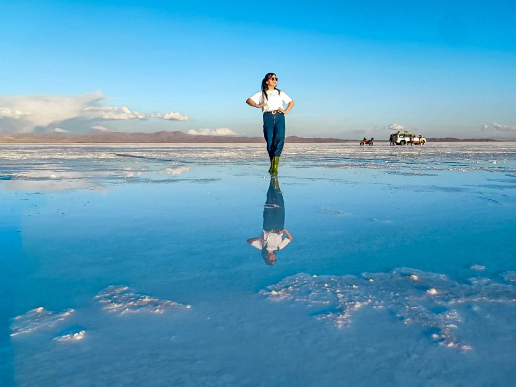 Viajera posando sobre el Salar de Uyuni, donde una fina capa de agua crea el impresionante "efecto espejo", reflejando su figura y el cielo en el cristal de sal.