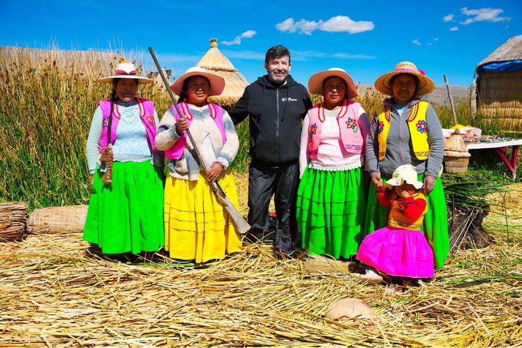 Otro turista participa en la demostración cultural de caza tradicional de aves con escopeta, junto a mujeres y niña nativas en las islas Uros.
