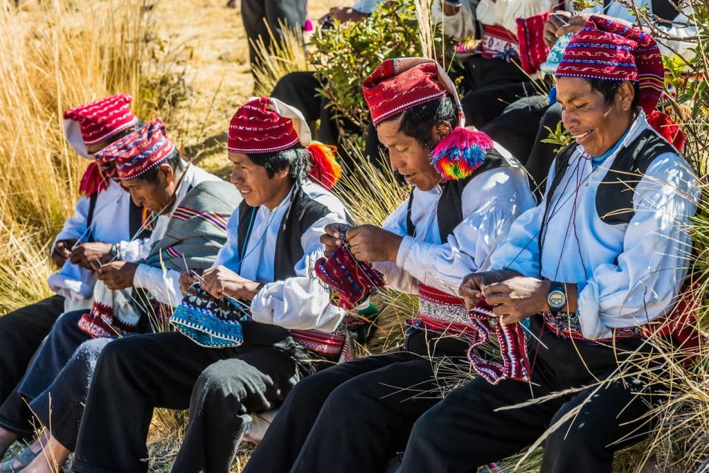 Hombres tejedores taquileños mostrando sus habilidades manuales en el tejido tradicional de chullos.
