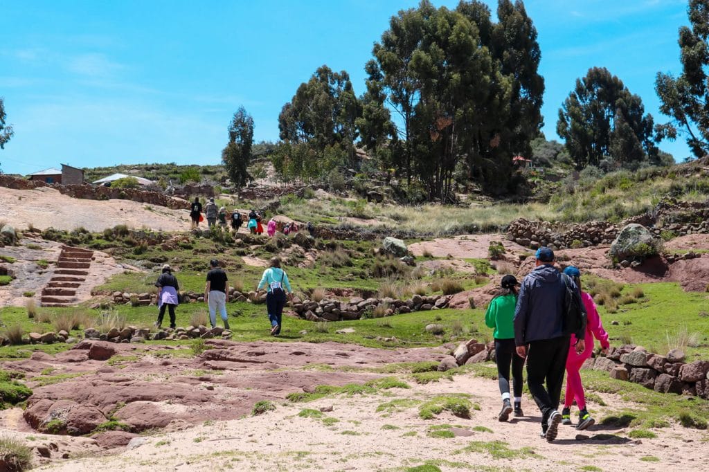 Ascenso de turistas por el sendero desde el puerto rústico de Luquina Chico, en dirección a las casas de familia.