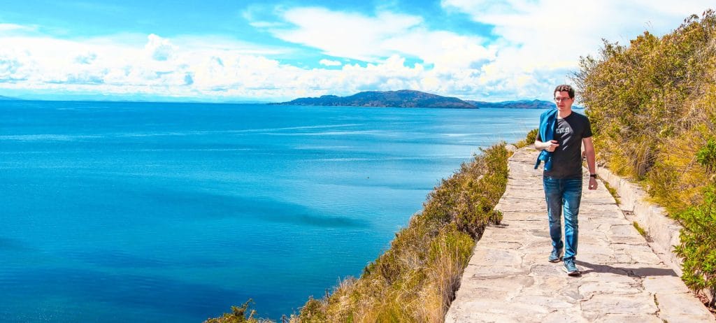 Turista en caminata por senderos de Taquile, con vista panorámica del Lago Titicaca.