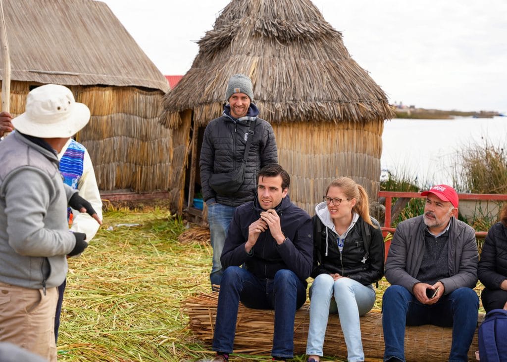 Guía turístico explica a viajeros la ingeniería de la totora para la construcción de islas Uros, Puno, Lago Titicaca.