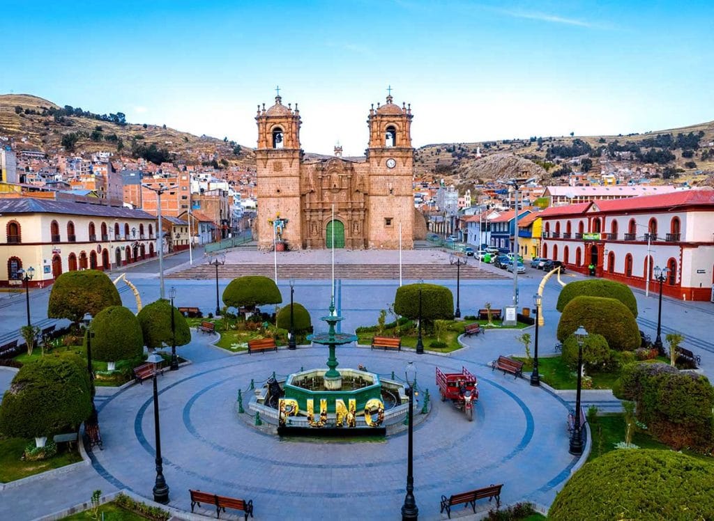 City tour Puno Catedral Museo Dreyer, Amanecer en Puno: Vista panorámica de la Plaza de Armas y la Catedral bañadas por los primeros rayos de sol dorados, destacando la arquitectura colonial.